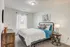 Bright and inviting bedroom with stylish decor, featuring a comfortable bed, rustic wooden dresser, and elegant artwork.