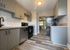 Chic modern kitchen with sleek cabinetry, stainless steel appliances, and elegant wood flooring, leading to a cozy, well-lit living area.