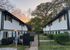 Charming apartment complex featuring two-story buildings with modern design, surrounded by lush greenery and a scenic sunset backdrop.