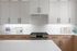 Sleek modern kitchen showcasing elegant white cabinets, luxurious countertops, and a state-of-the-art stainless steel oven.