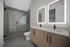 Modern bathroom featuring a sleek glass-enclosed shower, double vanity with illuminated mirrors, and elegant fixtures.