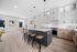 Modern open-concept kitchen and dining area with sleek cabinetry, large island with bar stools, and bright natural lighting.