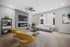 Modern living room with elegant furnishings, featuring a sleek fireplace, vibrant yellow chairs, and large windows offering ample natural light.