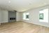 Bright and spacious living room with modern hardwood floors, elegant gray accent wall, and ample natural light from large windows.