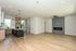 Modern open-concept living area with sleek kitchen, featuring wood flooring, pendant lighting, and a contemporary fireplace.