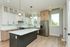 Sleek modern kitchen with elegant white cabinetry, a spacious island, stainless steel appliances, and natural wood flooring.