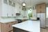 Modern kitchen with sleek cabinetry, large island, stainless steel appliances, and elegant pendant lighting.