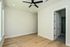 Bright and airy bedroom with elegant hardwood flooring, modern ceiling fan, and a sleek en-suite bathroom.