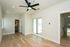 Bright and airy room with elegant hardwood floors, large sliding glass door to a sunlit balcony, and modern ceiling fan.