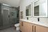 Contemporary bathroom showcasing a sleek double vanity with illuminated mirrors, spacious glass shower, and modern fixtures.