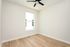 Bright, airy room with light hardwood floors and a sleek ceiling fan, perfect for personalization and comfort.