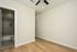 Bright room with elegant wooden flooring, ceiling fan, and a view into a modern bathroom.