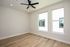 Bright and airy bedroom with modern ceiling fan and large windows, featuring elegant hardwood floors and a fresh, neutral palette.