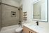 Modern bathroom design with a sleek vanity, illuminated mirror, chic shelving, and stylish black fixtures.