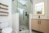 Elegant bathroom with modern glass shower, sleek vanity, and stylish shelving.