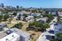 Aerial view of a thriving urban neighborhood showcasing modern townhouses, lush green spaces, and a bustling city skyline on the horizon.