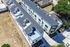 Modern aerial view of a sleek multi-story apartment complex with private balconies and contemporary architecture nestled in a serene neighborhood.