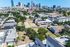 Aerial view of a vibrant urban landscape with greenery and modern housing, framed by a stunning city skyline.