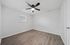 Bright and airy bedroom featuring modern wood flooring, sleek ceiling fan, and a large window for natural light.