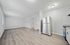 Modern apartment interior showcasing a bright, open living and kitchen area with sleek hardwood floors and stainless steel appliances.