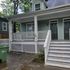 Charming green house with a welcoming front porch and white lattice accents, perfect for enjoying outdoor relaxation.