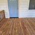 Inviting wooden porch with a charming blue door and white siding, perfect for relaxing afternoons.