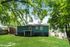 Charming backyard view of a blue house with lush green grass and mature trees, perfect for outdoor relaxation.