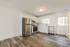 Modern kitchen with stainless steel appliances, white cabinetry, and elegant wood flooring, brightened by natural light from a window.