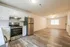 Charming open kitchen and living room with sleek stainless steel appliances, modern cabinetry, and elegant wood flooring.