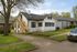 Charming suburban home with a wooden staircase, lush green lawn, and inviting porch in a peaceful neighborhood.