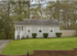 Charming single-story home with welcoming front porch, nestled on a spacious green lawn with a neat driveway and attractive brick retaining wall.