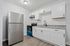 Modern kitchen with granite countertops, sleek stainless steel refrigerator, and stylish white cabinetry, perfect for contemporary living.
