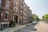 Charming historic apartment building with elegant brick facade, located on a serene, tree-lined street.