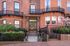 Charming brick apartment with elegant wrought iron balcony railings and blooming garden entrance.
