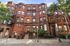 Charming brick apartment building with classic architecture, featuring elegant arched windows and a welcoming entrance in a vibrant urban setting.