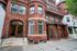 Charming historic red-brick apartment building with elegant archways and large windows, nestled in a vibrant urban setting.