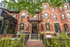 Charming urban brick building with stylish storefronts, lush greenery, and inviting entry steps.