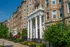 Elegant historic apartment building with regal columns, lush landscaping, and charming architectural details.