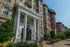 Charming historic apartment building with elegant neoclassical columns and lush landscaping, offering classic architectural beauty and urban elegance.