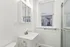 Bright and modern bathroom featuring a sleek white vanity, elegant fixtures, and a large window inviting natural light.