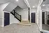 Elegant apartment entrance with sleek geometric flooring, modern staircase, and stylish dark doors for a sophisticated living experience.