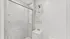 Bright and elegant bathroom featuring a marble-tiled shower with glass doors, sleek vanity, and modern light fixture.
