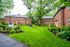 Charming brick apartment buildings with lush green lawns and mature trees, offering a serene and inviting community atmosphere.