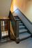 Welcoming staircase with classic design and warm lighting, leading to a charming upper level. Elegant glass door adds a touch of sophistication.