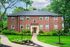 Charming brick apartment building surrounded by lush greenery and beautifully landscaped gardens, offering a serene living environment.