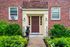 Charming brick apartment entrance with elegant foliage and a whimsical bear statue, creating a welcoming and unique fa&ccedil;ade.