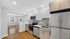 Modern kitchen with sleek stainless steel appliances, white cabinets, and an inviting open layout leading to a sunlit living area.