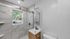 Modern bathroom featuring elegant marble tiles with a sleek glass shower, natural light, and stylish wood cabinetry.