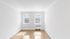 Sunny, minimalist room featuring pristine white walls, large windows, and elegant wooden flooring.