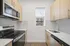 Modern kitchen featuring sleek stainless steel appliances, elegant herringbone backsplash, and natural wood cabinetry, filled with natural light.